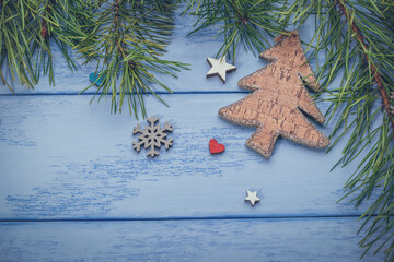 Christmas or New Year flat lay: pine branches, wooden Christmas tree and some decorations on the blue boards