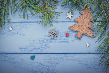 Christmas or New Year flat lay: pine branches, wooden Christmas tree and few decorations on the blue boards