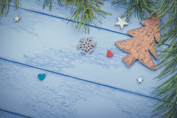 Christmas or New Year background: pine branches, wooden Christmas tree and some decorations on the blue boards