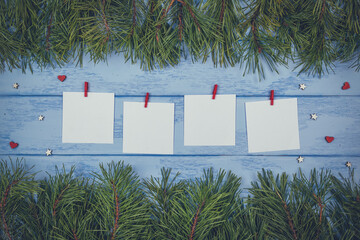 Christmas or New Year mock up: pine branches, decorative wooden hearts and white stickers with little clothespins on the blue boards