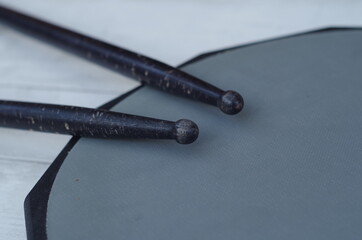 black drum sticks on rubber practice pad close up