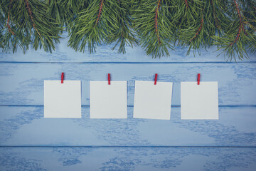 Christmas or New Year mock up: some pine branches and white stickers with red clothespins aligned straight on the blue boards
