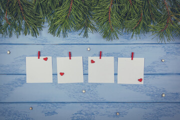 Christmas or New Year mock up: pine branches, white stickers with red clothespins and wooden decorative hearts and stars on the blue boards