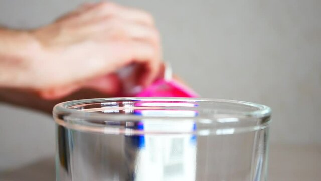 A man opens a milk carton and pours the milk into a glass close-up