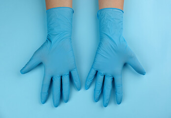 Person in medical gloves on light blue background, top view