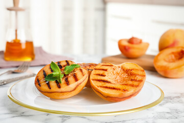 Delicious grilled peaches with mint on white marble table indoors
