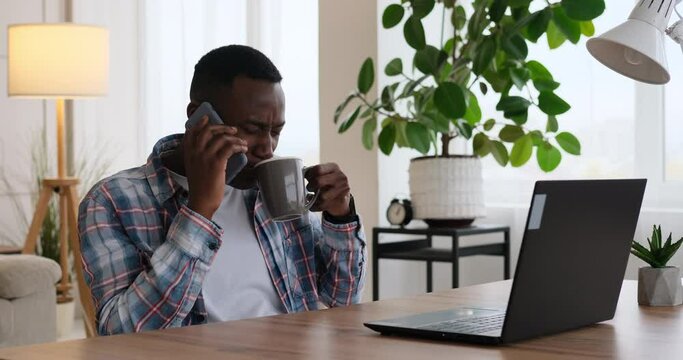Businessman having fun talking on mobile phone while working on office laptop