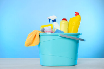 Bucket with different cleaning products and supplies on light table
