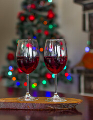 Two wineglass of red wine in front cozy and warm fireplace, in country house. Winter or autumn (fall) vacation. Happy New Year, Merry Christmas or saint Valentine's Day. Romantic evening for couple.