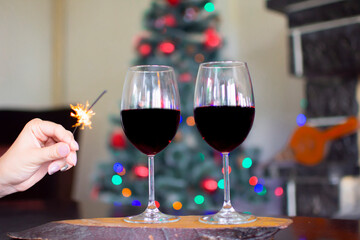 Two wineglass of red wine in front cozy and warm fireplace, in country house. Winter or autumn (fall) vacation. Happy New Year, Merry Christmas or saint Valentine's Day. Romantic evening for couple.