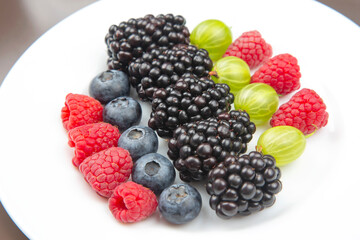 fresh different berries on a white plate. useful vitamin healthy food fruit. healthy vegetable breakfast