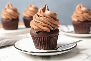 Delicious fresh chocolate cupcake on white marble table, closeup