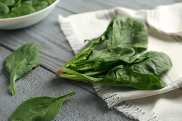 Fresh green healthy spinach leaves on grey wooden table, closeup