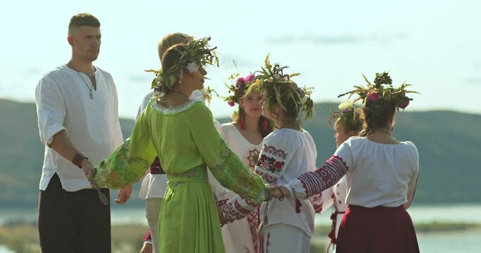 Beautiful and young women with wreaths on their heads dance in folk costumes, traditions and customs of the Slavic peoples. Folk dresses with ornaments, the holiday of Ivan Kupala. 4k, ProRes