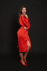 Fototapeta premium Happy woman in red dress on black background. Christmas party