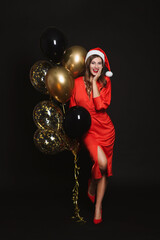 Happy woman in Santa hat with air balloons on black background. Christmas party