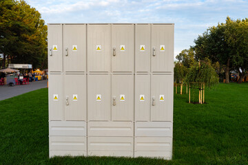 Outdoor electrical cabinets in the park. Plastic anti-vandal electrical cabinet. Open-air electrical cabinet. Safe boxes with electric poles on the lawn. Concept -.electrification of parks.