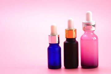 Serum bottles. Luxury colorful glass serum bottles on pink color background.