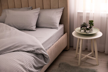 Fototapeta na wymiar Comfortable bed with soft blanket near window indoors