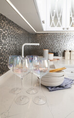 Beautiful ceramic dishware and glasses on countertop in modern kitchen