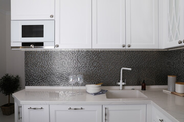 Beautiful ceramic dishware and glasses on countertop in modern kitchen