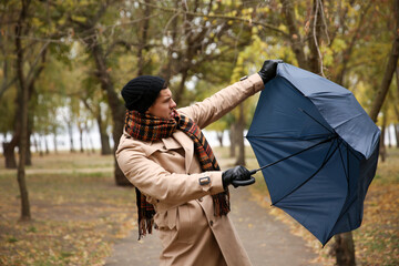 Man with blue umbrella caught in gust of wind outdoors