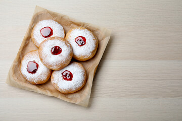 Hanukkah doughnuts with jelly and sugar powder served on wooden table, top view. Space for text