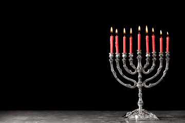 Silver menorah with burning candles on table against black background, space for text. Hanukkah...