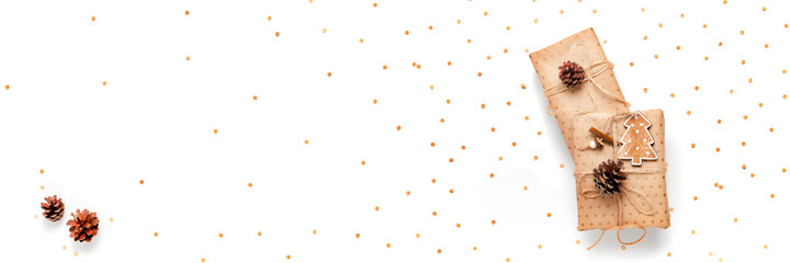 Gift box wrapped in craft paper decorated with pine cone on white background, long banner, copy space, top view