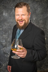Solid smiling bearded man in suit with glass of whisky