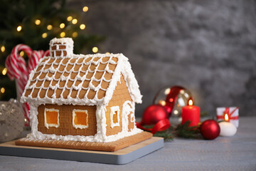 Beautiful gingerbread house decorated with icing on grey wooden table