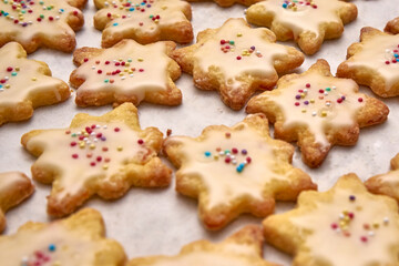 Biscuits Coated With Sugar Icing With Decorative Color Balls On A Sheet Of White Baking Paper