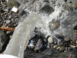 放物線を描いて石だらけの地面に落ちる水