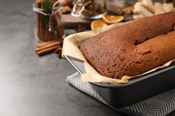 Delicious gingerbread cake in baking dish on grey table, space for text