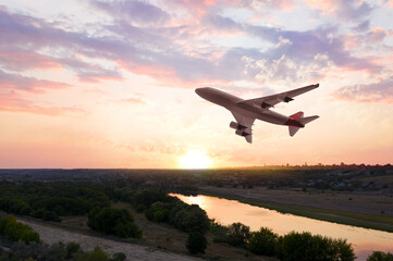 Fototapeta na wymiar Modern airplane flying in sky during sunset