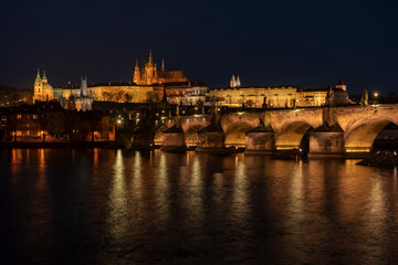 Fototapeta premium . prague castle and charles bridge and st. vita church lights from street lights are reflected on the surface of the vltava river in the center of prague at night in the czech republic