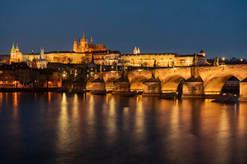 . prague castle and charles bridge and st. vita church lights from street lights are reflected on the surface of the vltava river in the center of prague at night in the czech republic
