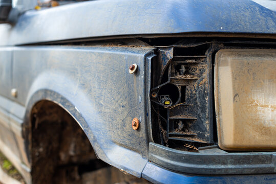 Damaged rusty blue car with repaired headlamp and missing turn light pickup abandoned in forest nature problem in Bulgaria, Eastern Europe