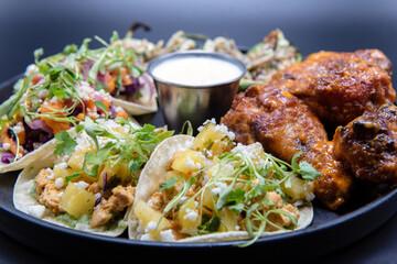 Delicious appetizer sampler plate with chicken and steak tacos, poppers, and buffalo wings makes the mouth water and the stomach growl.