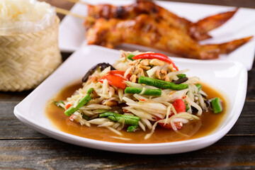 Thai food (Som Tum), Spicy green papaya salad eating with grilled chicken wing and sticky rice