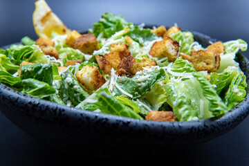 Delicious Caesar salad topped with parmesean cheese and dressing makes the mouth water and the stomach growl.