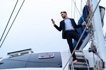 businessman with smart phone on cruise yacht with background of sea and white sky. Concept business...