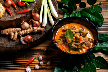 THAI BEEF RED CURRY. Thailand tradition red curry soup with beef  and coconut milk. Red Curry with ingredient in Black plate on woodden background.