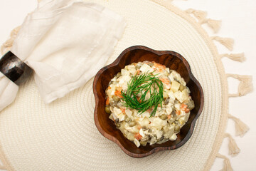 Tradition New Year and Christmas Russian salad "Olivier"on white rustic background. Boiled vegetables and meat with mayonnaise in wooden bowl top view. The most famous starter in Russian cuisine.