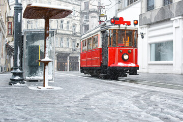 Red nostalgic tram is moving on the Istiklal street in winter day with snow. Istiklal Street is the...