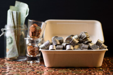 Concepts of finance, investing in assets with interest, dividend and profit. Coins in a box made of green products on a black background.