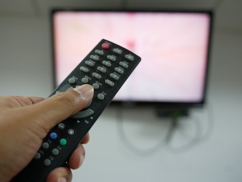 closeup of hand with the remote control television and presses the button.