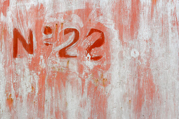 Number 22 sprayed on wall graffiti red on red and grey rust texture