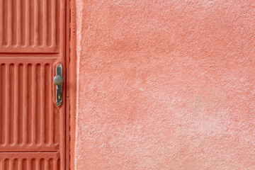 Red orange door wth pink wall of old and shabby house in rural Bulgaria