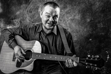 Obraz premium Mature musician plays acoustic guitar emotional studio portrait.